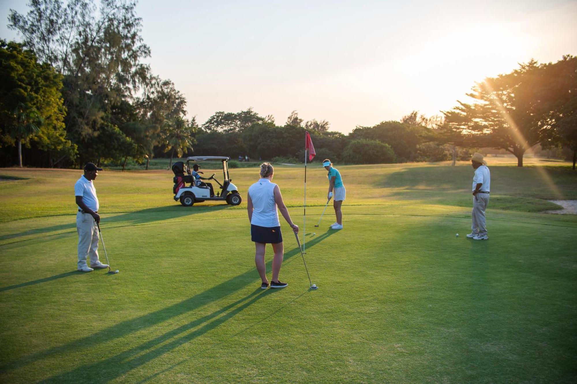 Diamonds Leisure Beach & Golf Resort Diani Beach Bagian luar foto Golfers putting on the 18th green at the Royal Pines Resort